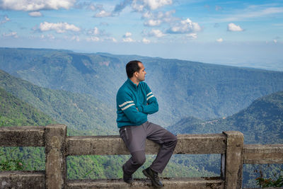 Young man watching the mountain range with bright blue sky at afternoon from flat angle