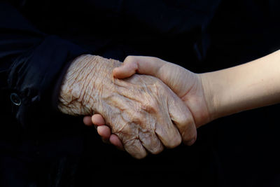 Midsection of woman with hands over black background