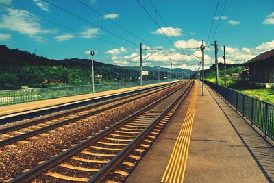 Railroad tracks against cloudy sky