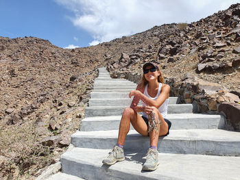 Portrait of woman sitting on staircase against mountain