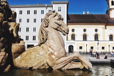 Statue against buildings with people in background