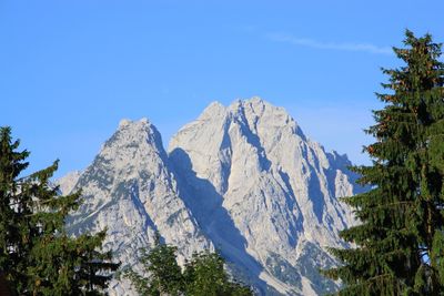 Low angle view of snowcapped mountains against clear blue sky