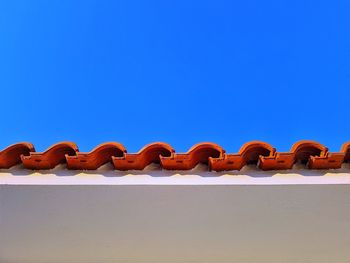 Low angle view of roof tiles against clear blue sky