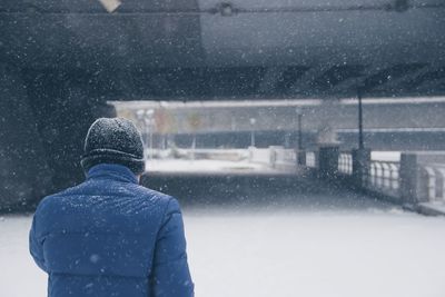 Rear view of man on snow covered road in city