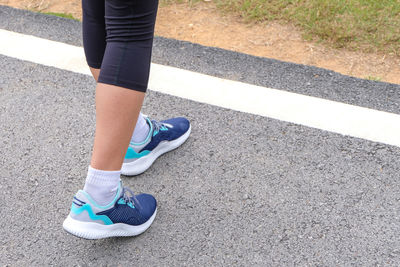 Low section of woman standing on road