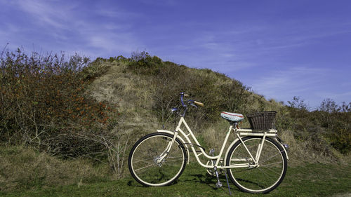 Bicycle parked on field against sky