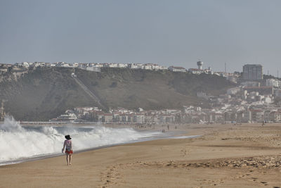 Rear view of man on beach against sky