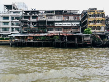 River by buildings in city against sky