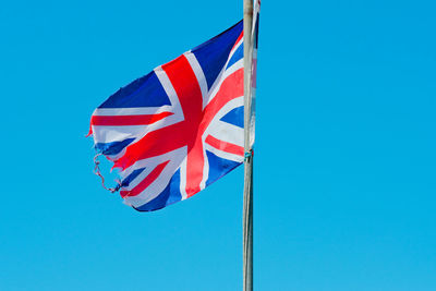 Low angle view of flag against blue sky