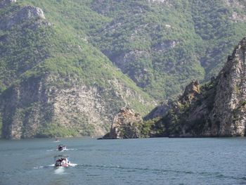 People on sea by mountains