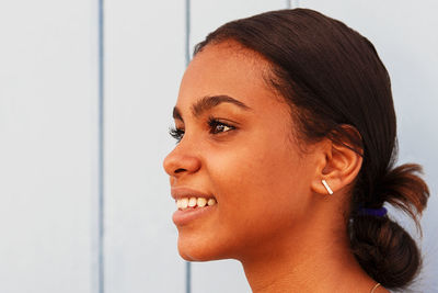 Portrait of smiling young woman against wall