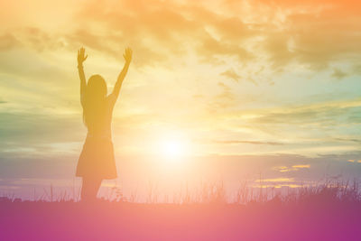 Silhouette woman standing on field against sky during sunset