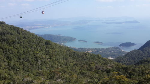 Overhead cable car over mountains against sky