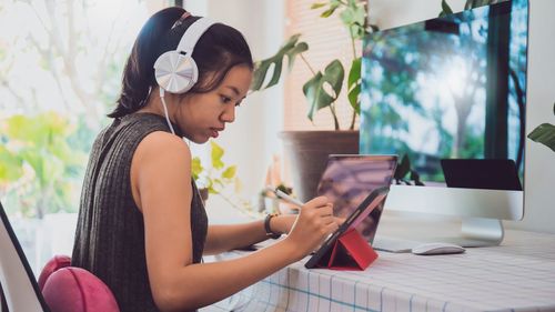 Side view of young woman using mobile phone at home