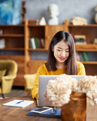 Young smiling woman working on laptop at home