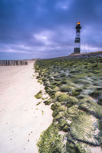 Lighthouse by sea against sky