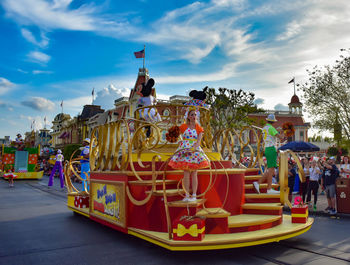 Carousel in amusement park against sky in city