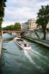 Boat in river against sky in city