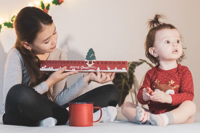 Two girls with an advent calendar and candies on the bed.