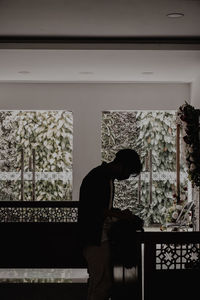 Side view of silhouette man standing against window