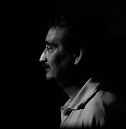 Profile view of thoughtful man against black background