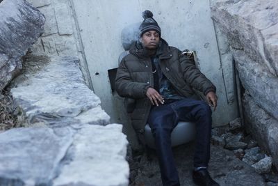 Portrait of young man smoking while sitting on chair during winter