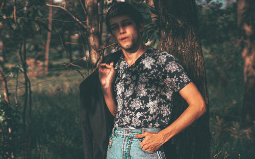Young man standing against trees in forest