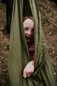 Vertical of young girl wrapped up in hammock outside