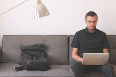 Man working on laptop while sitting on sofa