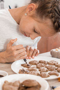 Preparing to celebrate halloween and preparing a treat. a girl paints halloween cookies 