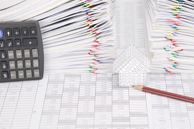 High angle view of model house with pencil and calculator on financial documents