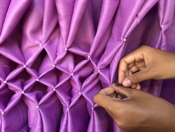 Close-up of hands making decoration with purple textile