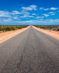 Road passing through land against sky