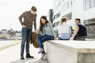 Woman showing smart phone to friend at university