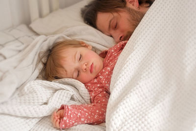 Father and his little daughter toddler girl sleeping together. healthy sleep. happy loving family