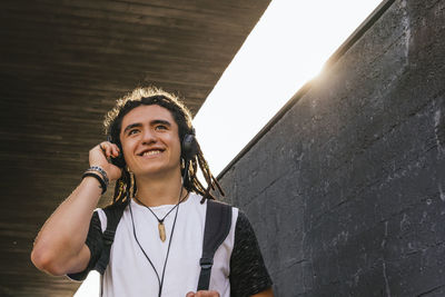 Portrait of smiling young woman standing against wall