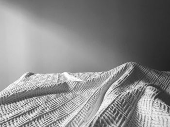 Close-up of blanket on bed against wall at home