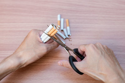 Close-up of hand holding cigarette on table