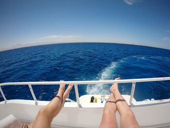 Low section of man on boat in sea against sky