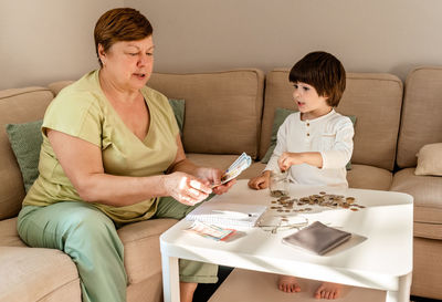 Senior woman with little child counting money americain dollars and euro at home  planning budget