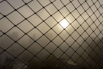 Full frame shot of chainlink fence against sky during sunset