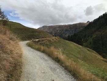 Scenic view of road by mountains against sky