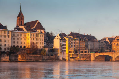 Buildings by river against sky