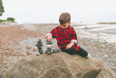 Rear view of boy sitting on rock