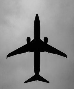 Directly below shot of silhouette airplane flying against sky