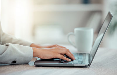 Midsection of woman using laptop at home