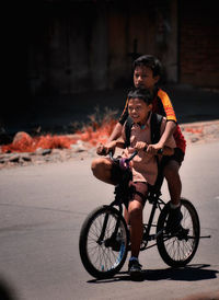 Friends riding bicycle on road