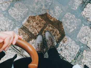 Low section of person standing on footpath by puddle