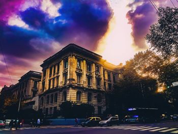 View of city street against cloudy sky at sunset