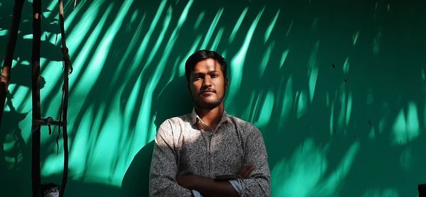 Portrait of young man standing against wall